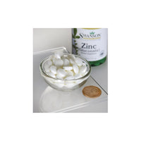 Thumbnail for A bowl of white capsules next to a bottle of Swanson Zinc Gluconate 30 mg 250 Tablets supplements for daily wellness.