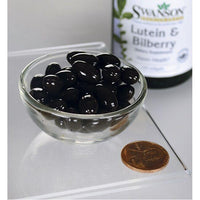 Thumbnail for A glass bowl containing dark gel capsules next to a penny for scale, with a bottle of Swanson's Lutein Esters 6 mg & Bilberry 20 mg 120 Softgels for eye health in the background.