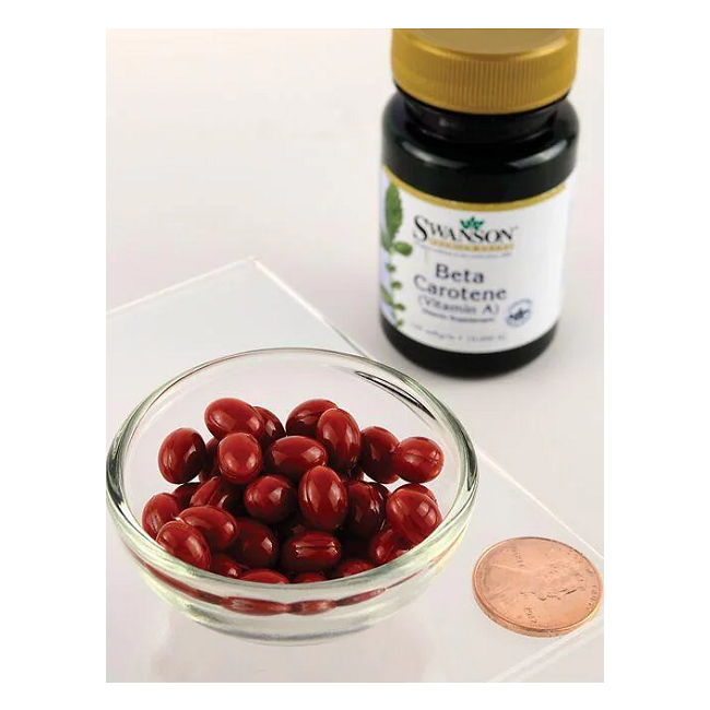 A glass bowl filled with Swanson Beta-Carotene (Vitamin A) 10000 IU capsules sits adjacent to its bottle, showcasing benefits for vision and skin health, with a penny for scale.