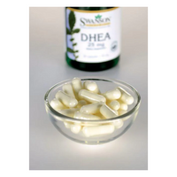 Thumbnail for A small glass bowl filled with white capsules is in the foreground, while a blurred bottle labeled 