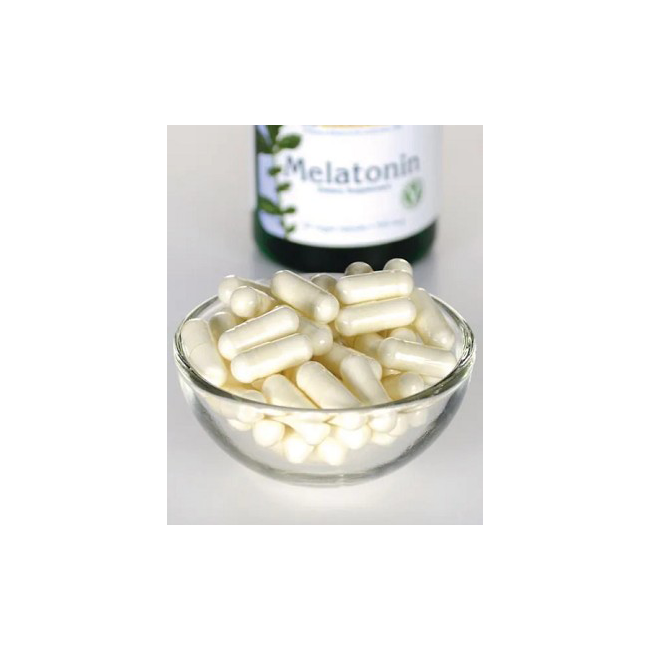 A small glass bowl with white capsules sits in front of a partially visible Swanson Extra Low Dose Melatonin 500 mcg bottle, highlighting the sleep aid's jet lag relief.