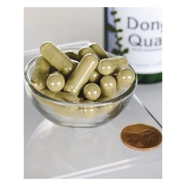 A glass bowl filled with Swanson's Dong Quai 530 mg capsules sits beside a penny on a reflective surface, hinting at the benefits of traditional Chinese medicine, with a partially visible bottle in the background.