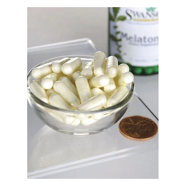 A small glass bowl of white capsules sits next to a US penny on a clear surface. In the background, a partially visible Swanson bottle reads "Melatonin - 1 mg 120 capsules," suggesting support for the sleep-wake cycle.