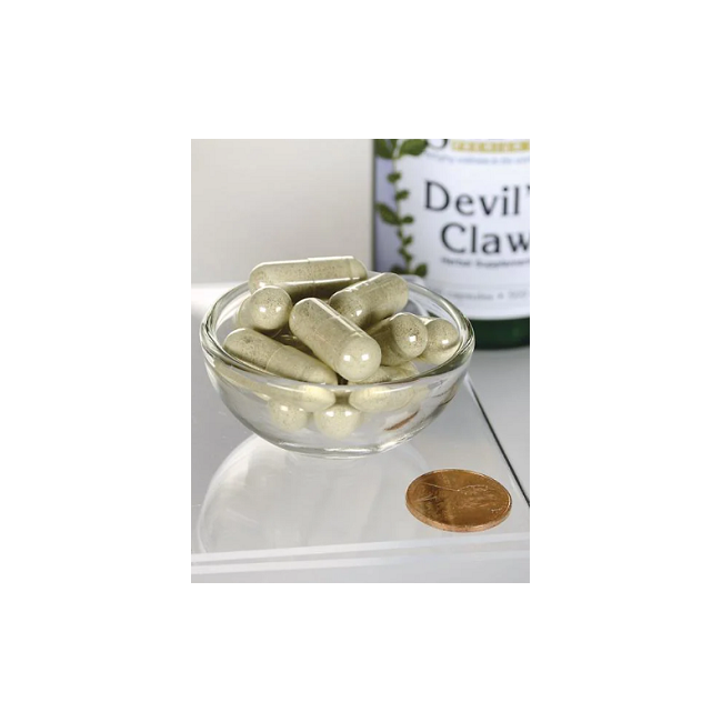 A small glass bowl with several capsules sits beside a coin, while a bottle labeled "Devil's Claw 500 mg 100 Capsules" by Swanson is in the background, emphasizing its traditional African medicine roots reputed for aiding joint health.