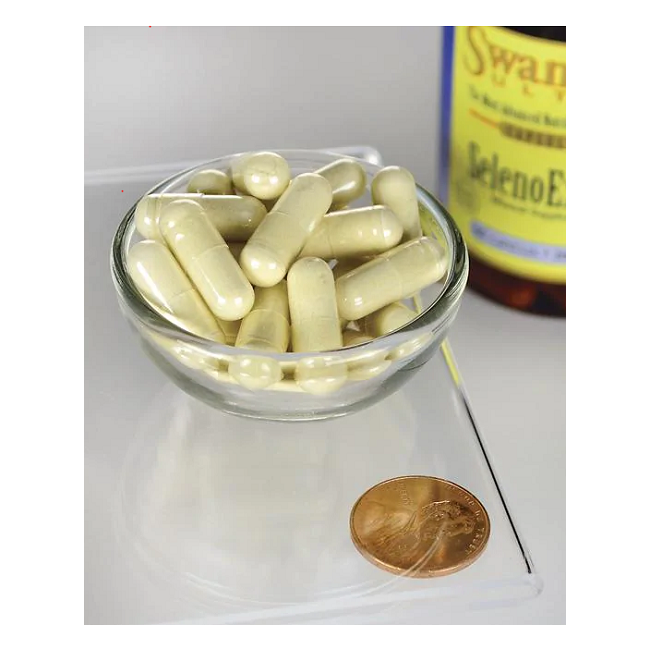 A small glass bowl holding yellow selenium capsules lies on a transparent surface next to a penny for size reference. In the background is a partially visible bottle labeled "Selenium - 200 mcg 60 capsules SelenoExcell" by Swanson, emphasizing its cardiovascular care benefits.