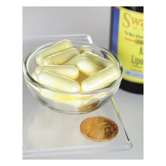 A clear bowl of yellow capsules labeled "Swanson Alpha Lipoic Acid 300 mg" sits on a glass surface. A nearby penny offers size reference, with a blurred bottle in the background.