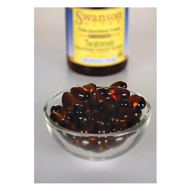 A clear bowl of dark brown capsules sits before a blurred Swanson bottle, emphasizing the potency of annatto-derived tocotrienols in each 50 mg softgel.