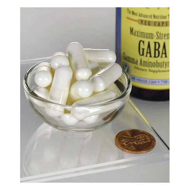 A small glass bowl filled with white capsules sits next to a penny for scale, promoting sleep and relaxation, with a partially visible bottle of "Swanson GABA 750 mg 60 Veggie Capsules - Maximum Strength" in the background.