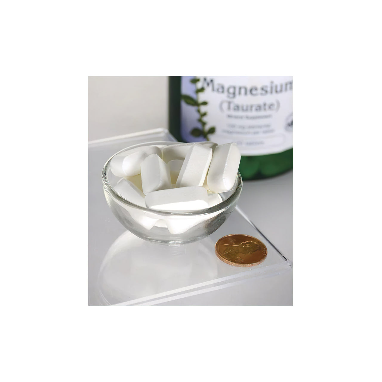 A bottle of Swanson Magnesium Taurate 100 mg 120 tab sitting next to a bowl of white pills.