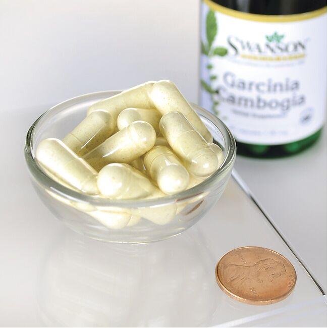 A bottle of Swanson's Garcinia Cambogia 5:1 Extract - 60 capsules and a penny on a table.
