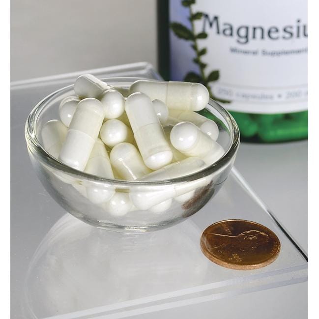 A bowl of white pills next to a bottle of Swanson Magnesium Oxide - 200 mg 250 capsules.