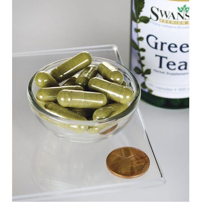 A bottle of Swanson Green Tea - 500 mg 100 capsules with a penny next to it.