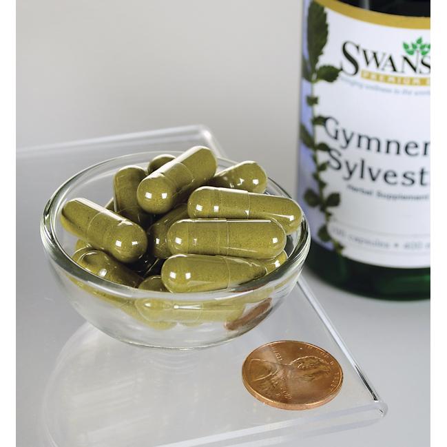 A bottle of Swanson Gymnema Sylvestre Leaf - 400 mg 100 capsules with a penny in a bowl.