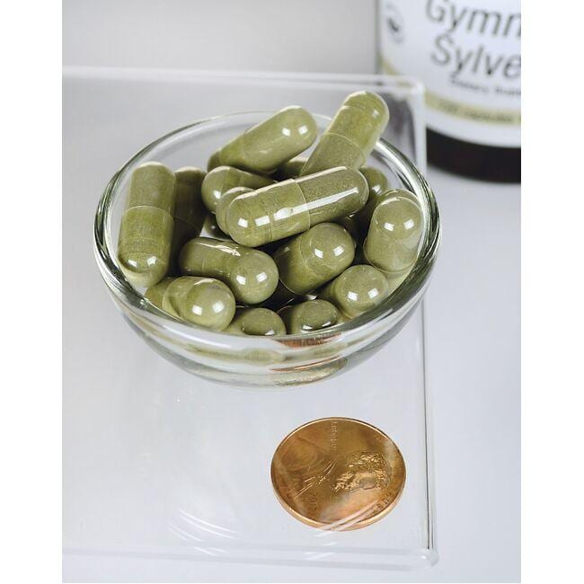A bowl of Swanson Gymnema Sylvestre Extract - 300 mg 120 capsules next to a coin.
