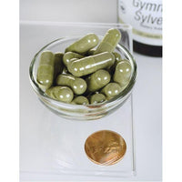 Thumbnail for A bowl of Swanson Gymnema Sylvestre Extract - 300 mg 120 capsules next to a coin.