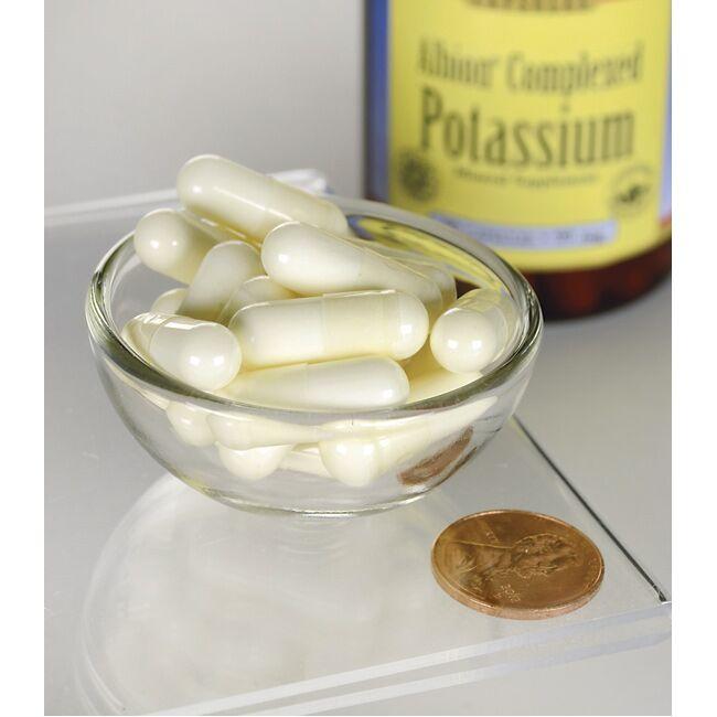 A bottle of Swanson Potassium - 99 mg 90 capsules Albion Chelated with a coin next to it, promoting the benefits of chelated potassium for the transport of glucose and maintaining healthy blood pressure.