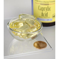 Thumbnail for Swanson's Caprylic Acid - 600 mg 60 softgel dietary supplement capsules in a bowl next to a coin.
