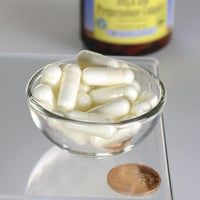Thumbnail for A bowl of white Swanson DHEA - 25 mg and Pregnenolone - 100 mg Complex 60 Veggie Capsules with a penny for scale and a blurred bottle in the background.