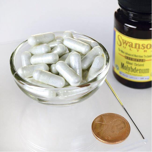 A bowl of Molybdenum - 400 mcg 60 capsules Albion Chelated pills next to a penny by Swanson.